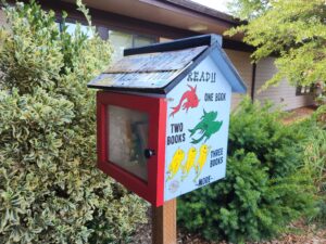 Photo Pollywog's Free Little Library showing red door, license plate roof and Dr. Seuss characters painted on the side.